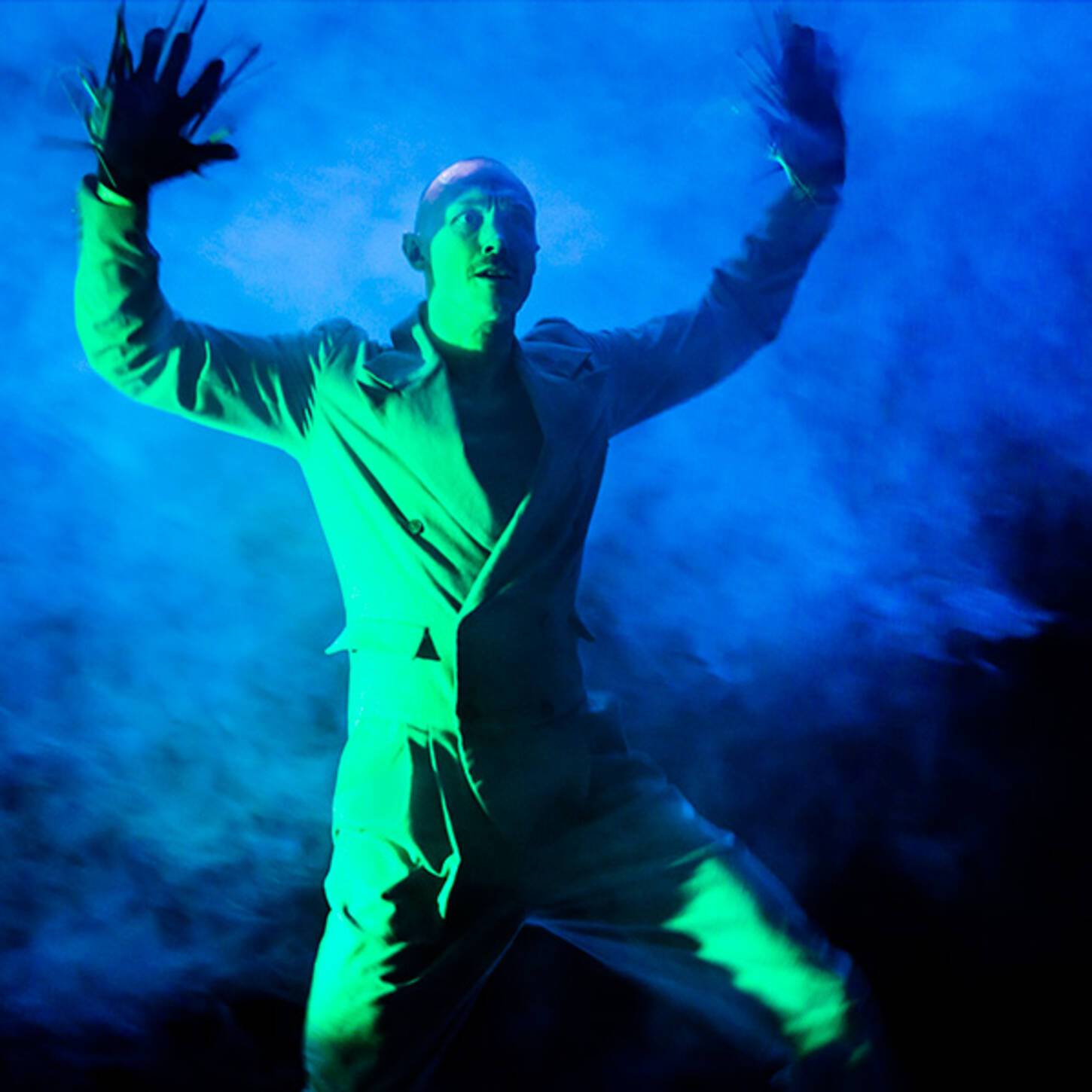 Danser in pak met op de achtergrond veel rook in groen licht