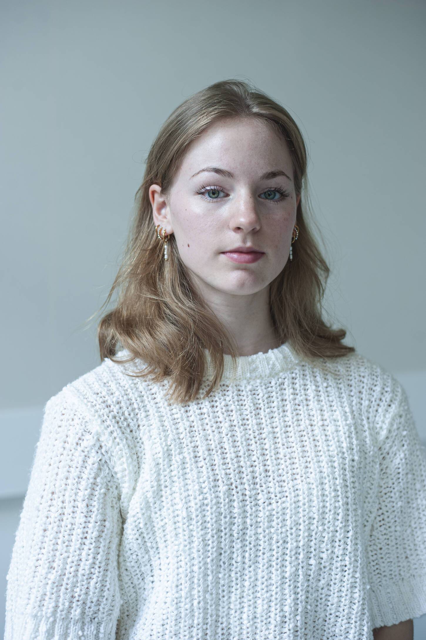 Jonge neutraal kijkende vrouw in witte wollen trui