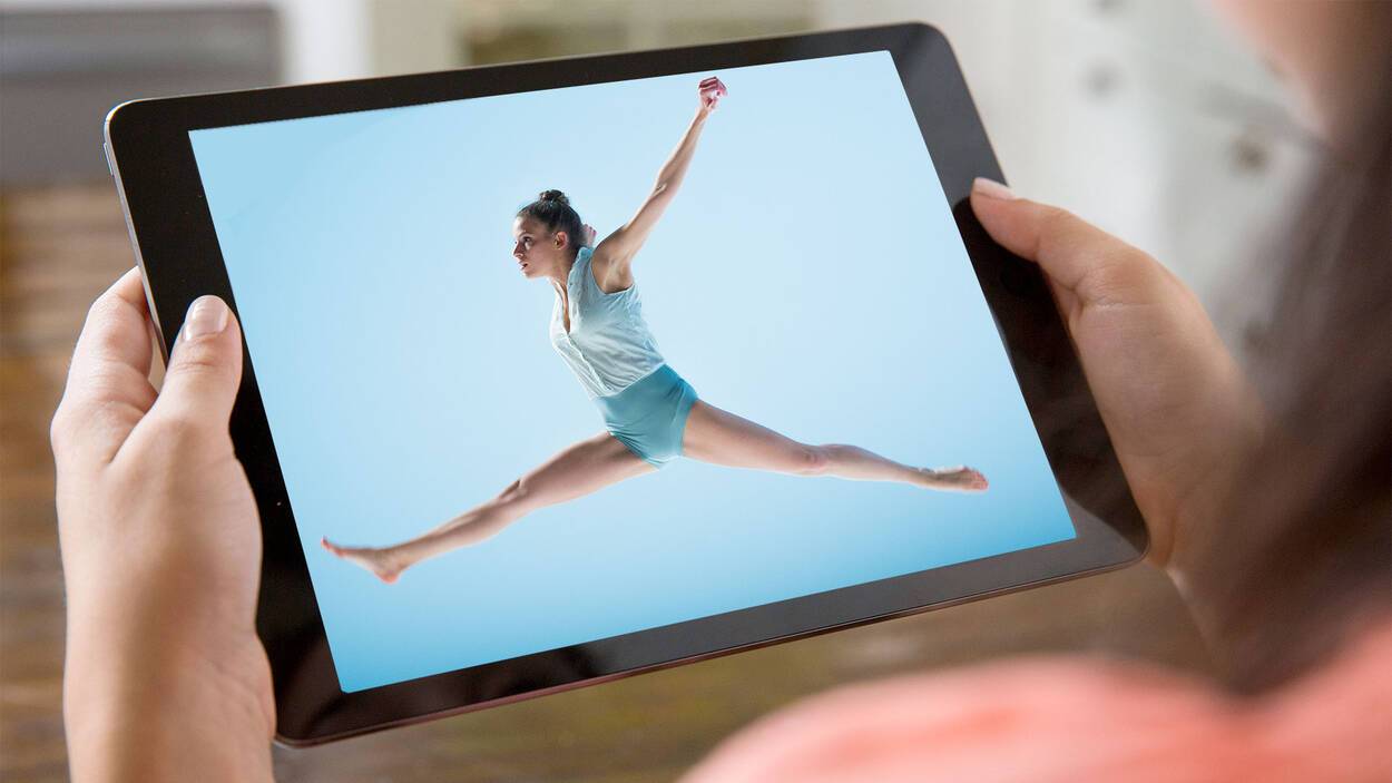 Danseres op blauwe achtergrond doet een sprong, en wordt bekeken op een tablet