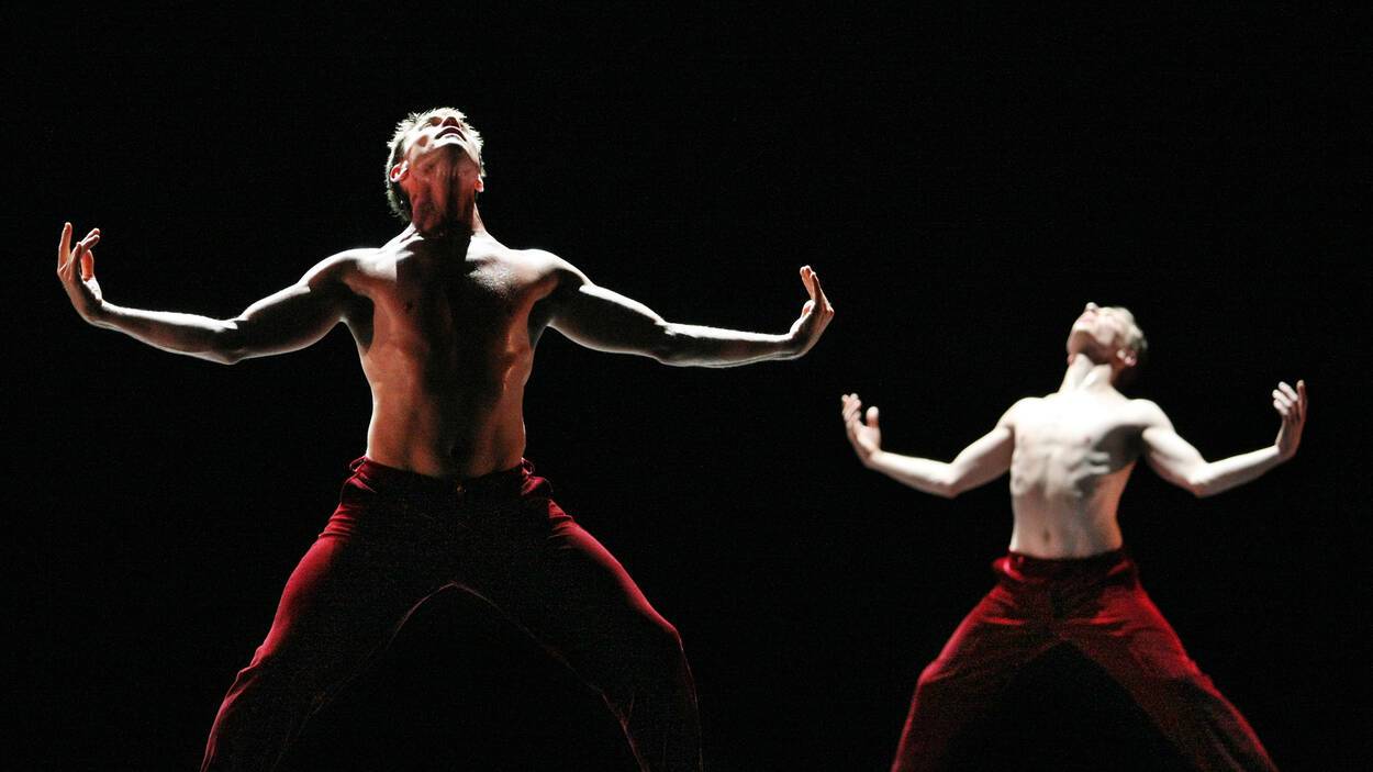 Twee dansers met ontbloot bovenlichaam met de armen krachtig gespreid