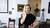 A woman in a black dress standing in a living room.