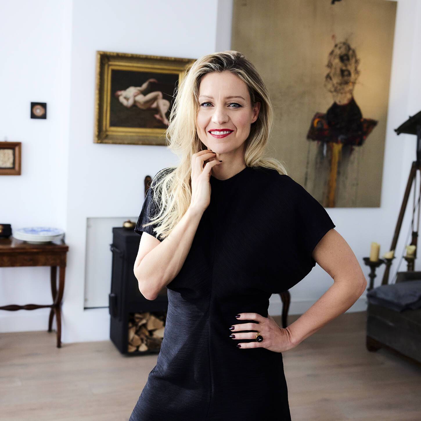 A woman in a black dress standing in a living room.