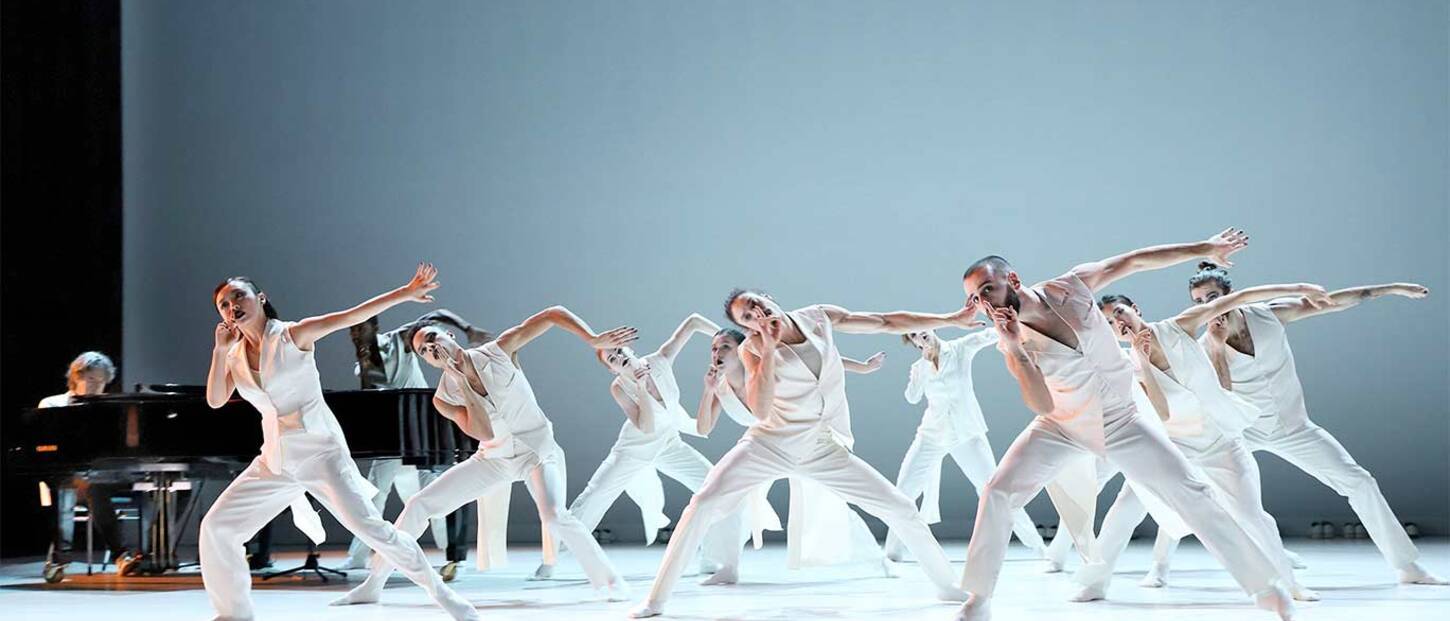 Beeld uit Pas de Deux met dansers in het wit en op de achtergrond een vleugel met daaraan Michiel Borstlap - foto Hans Gerritsen