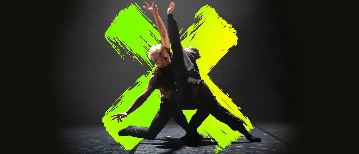 Twee dansers in het zwart met armen geopend en geknield op de vloer. Op de achtergrond een neongeelgroen kruis.