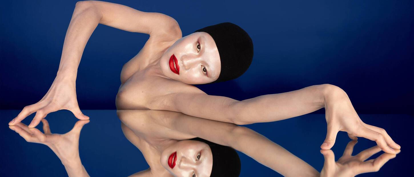Vrouw met rode lippen die mysterieus kijkt met spiegelbeeld