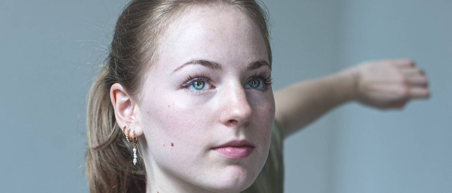 Glimlachende vrouw met licht geheven hoofd en haar armen wijd