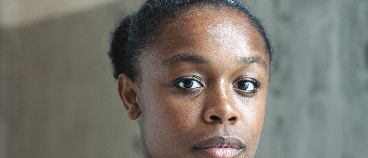 Serieus kijkende jonge vrouw met witte top en ketting