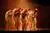 Groep van dansers in lichte kleding in oranjekleurig licht