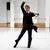 Een danser met een zwarte broek, zwarte jas en wit overhemd kijkt intens voor zich uit terwijl hij danst in de studio van Scapino.