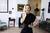 A woman in a black dress standing in a living room.